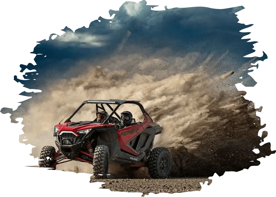 Red side-by-side UTV kicking up sand on a desert trail
